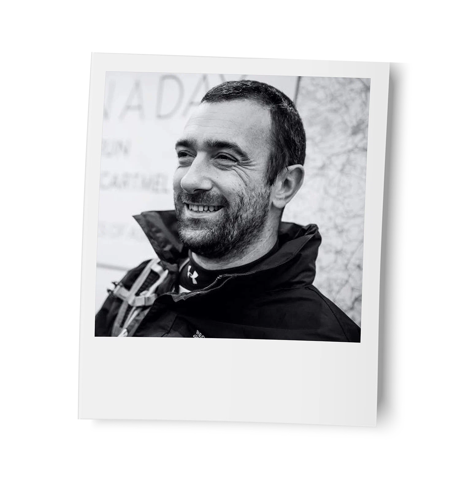 Black and white photo of Barry Hayes wearing a jacket with a backpack, outdoors.